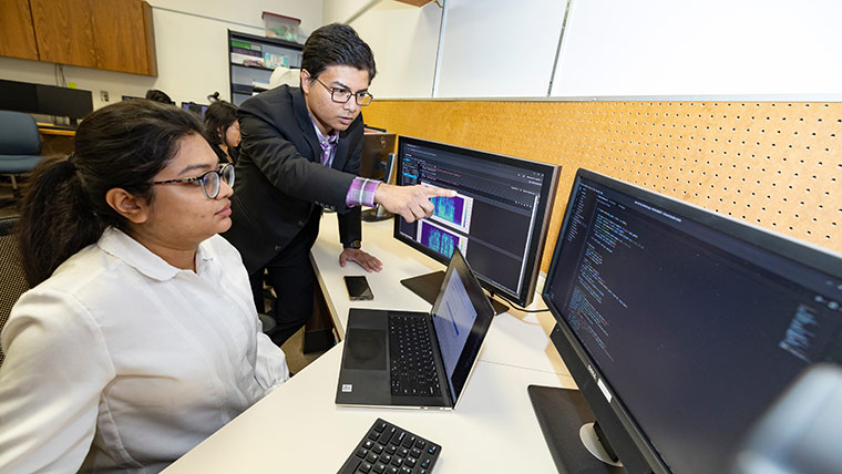 Computer science professor Dr. Razib Iqbal instructs a student who's working on computer code.