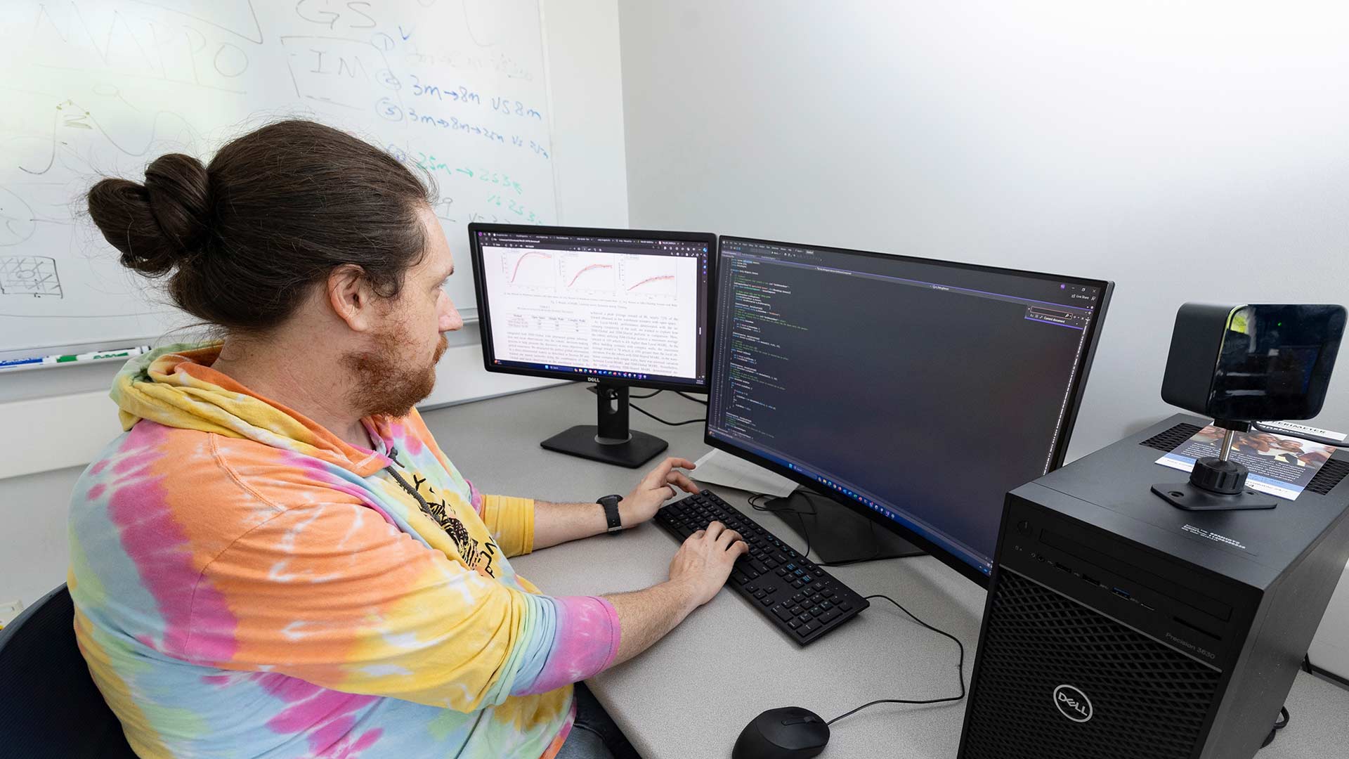 A computer science graduate student works on code at a computer station in a research lab on campus.