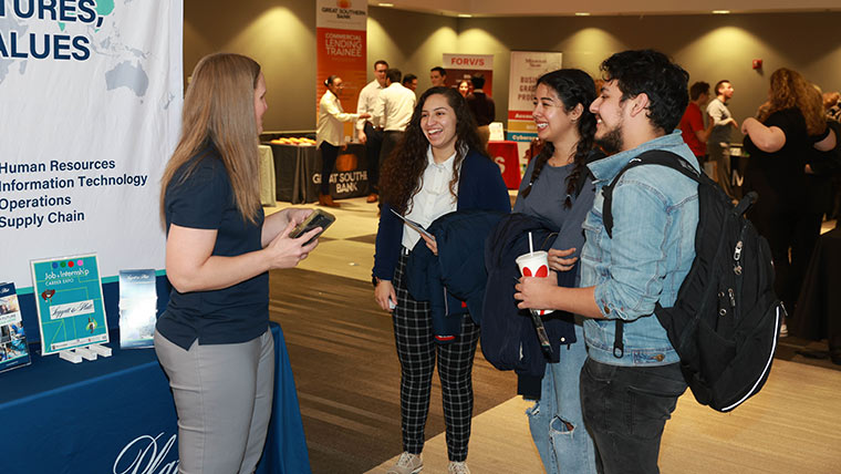 Three students talking with a company rep at a career fair event on campus.