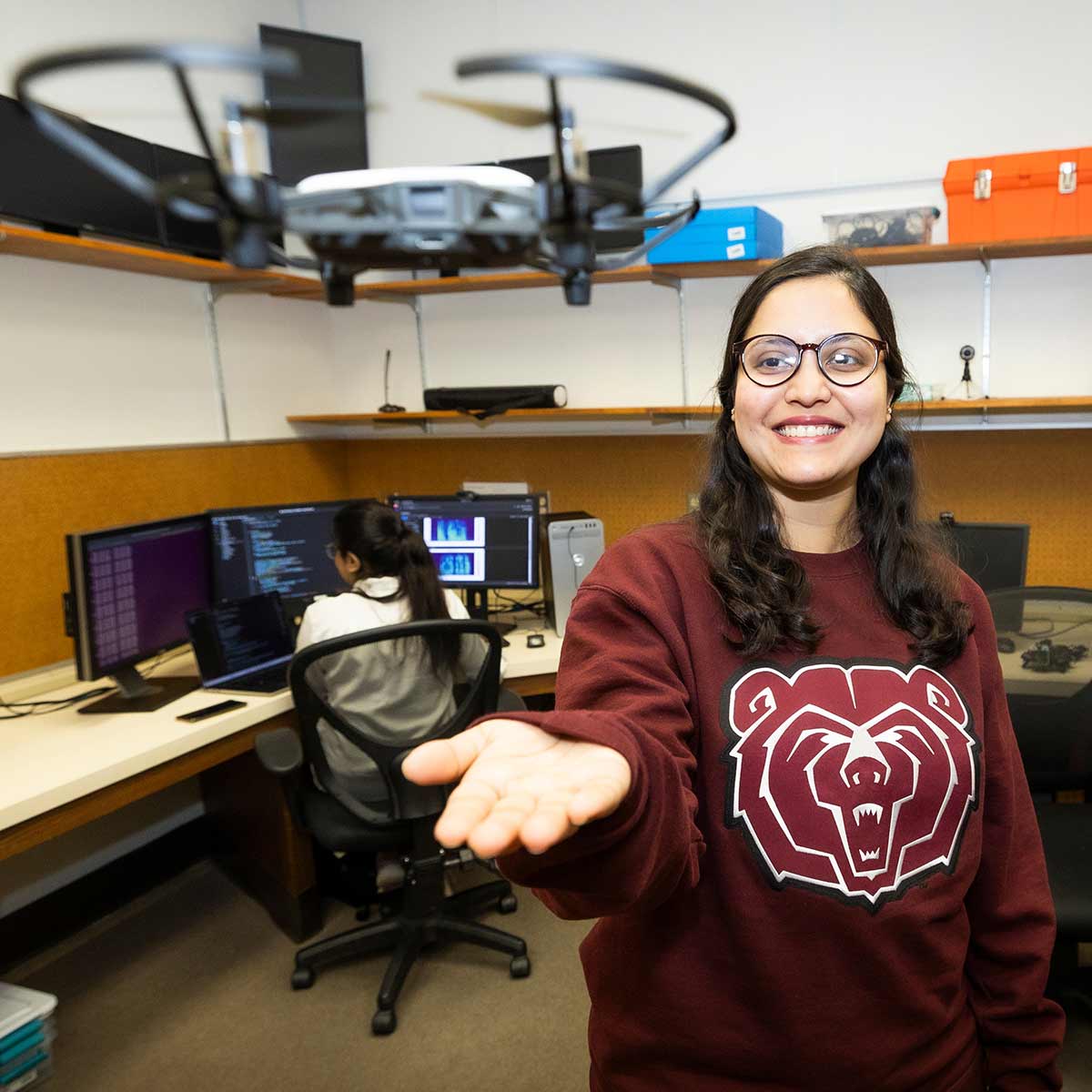 Jeniya Sultana holds up a drone for take-off in a computer science research lab