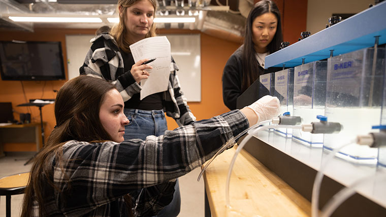 Three female engineering students conduct water testing during an Environmental engineering lab.