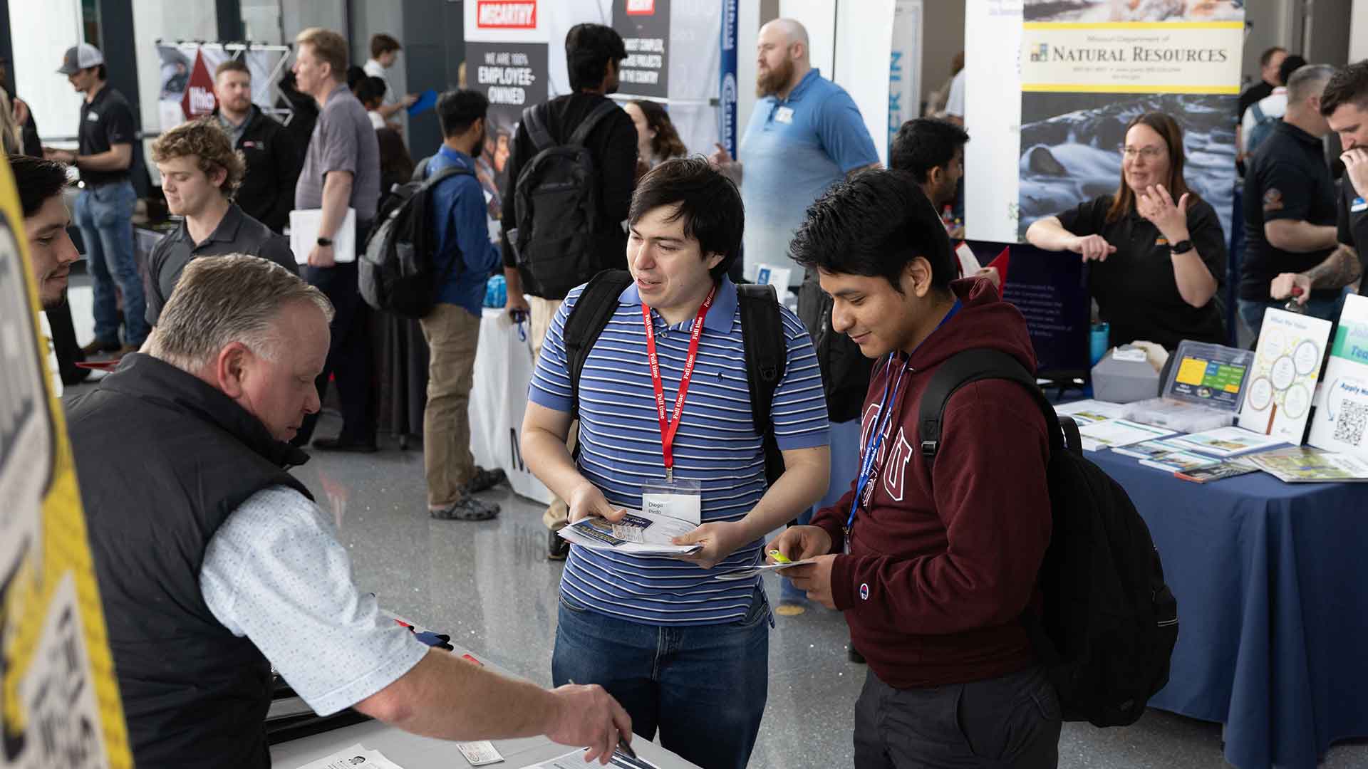 Two Missouri State students meeting a vendor at a career fair event.